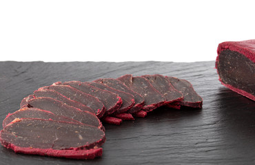 Cured meat on a slate board. Close-up of basturma sliced into pieces.