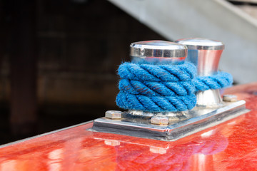 Detail of blue rope coiled around a steel bollard at a yacht