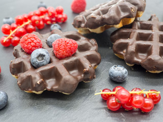 delicious chocolate covered waffles with forest berries on slate