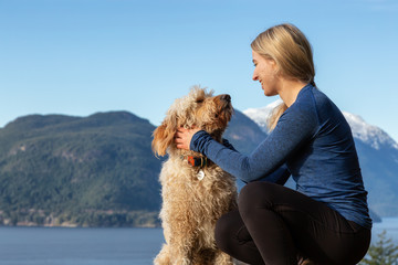 Adventurous Girl Hiking on top of a Mountain with a dog during a colorful sunset. Taken on Tunnel Bluffs Hike, near Vancouver and Squamish, British Columbia, Canada.