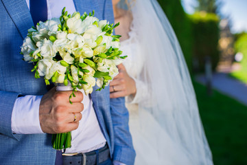 Wedding bouquet holding in a hands of couple.