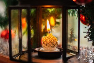 Candle in a Candleholder close-up with a candle on the background of spruce branches, red Christmas balls and silver tinsel. Christmas candle. Christmas toys, snow, Merry Christmas.