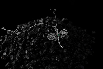 Unique handmade white gold dragonfly pendant with an emerald on a bunch of small black stones