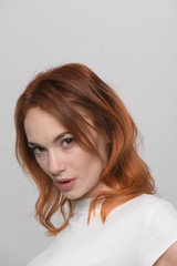 A young red-haired woman's face close-up is visible only part of the chin; the upper part is cut off from her with a decisive confident look from underneath.