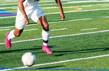 Soccer player in white uniform running after the ball