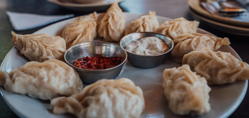 A dish of the tibetan boiled momo with a sauce. Momo is a dish of dough with a filling.