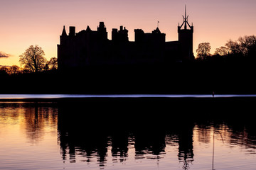 Silhouette of an old castle on the lake against the backdrop of the rising sun. Linlithgow Palace, Scotland - obrazy, fototapety, plakaty
