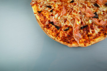Pepperoni pizza. spicy salami, mozzarella, chilli, gherkins. Wooden plate. Gray background. Restaurant