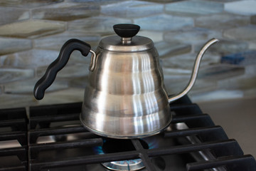 making pour over coffee with a stainless steel kettle on a gas stove