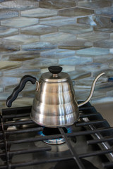 making pour over coffee with a stainless steel kettle on a gas stove