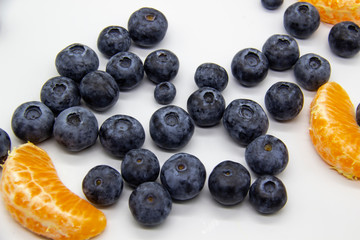 Fresh blueberry  with mandarin slices on white background. A composition of the blueberries and mandarin pieces which is organic and healthy. The berries and fruit full of vitamins.