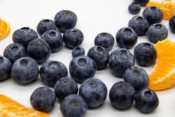 Fresh blueberry  with mandarin slices on white background. A composition of the blueberries and mandarin pieces which is organic and healthy. The berries and fruit full of vitamins.