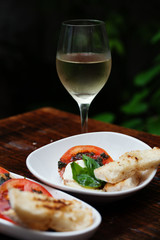 Mozzarella tomato albahaca plate with a glass of white wine