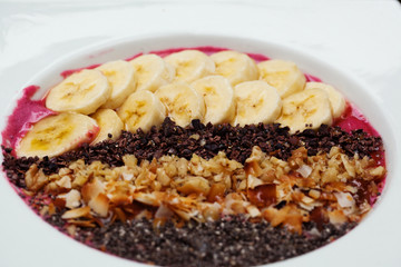 Acai bowl of purple yogurt with banana, chocolate chips, coconut, walnuts and chia on top 