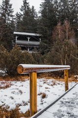 View on snowy path in Jezerní slať with lookout tower - peat bog near Kvilda in National Park of the Czech Bohemian forests, Czech Republic.