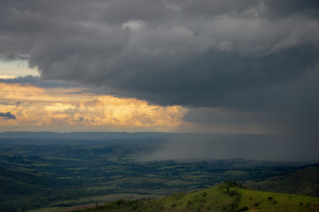 Fototapeta na wymiar Heavy rain falling into the green fields of Brazil at the sunset
