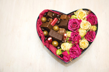 heart shaped gift box with candy and flowers inside on white