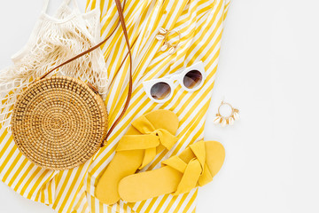 Yellow dress with stripes with slippers, sunglass, and bamboo bag. Women's stylish summer outfit. Trendy clothes. Flat lay, top view. - obrazy, fototapety, plakaty