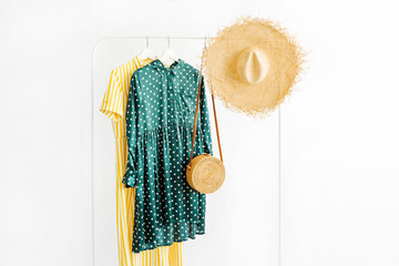 Summer dresses and straw hat with bamboo bag on hanger on white background. Elegant   fashion...