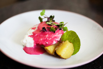 Decorative dinner plate of eggs, potatoes and a pink sauce