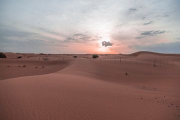 Fototapeta na wymiar sunrise on desert with sand dunes that is with fence