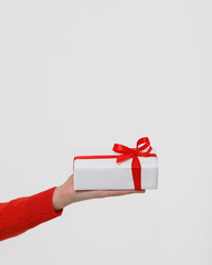 Close up of man hand holding white wrapped gift box with red ribbon, isolated on white background, side view, copy space. Holiday pattern. Valentines day, birthday celebration concept