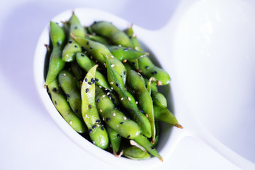 Edamame in the shell on a white plate with a white background