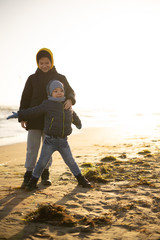 Two brothers, 10 years old and 4 years old, play and have fun on the seashore on a sunny winter day.