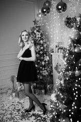 Christmas. Beautiful smiling woman. Fashion. Makeup. Healthy long hair style. Elegant lady in dress over lights background. Young woman in dress smiles and poses on the background of decorated room