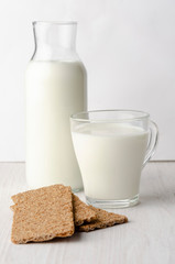A glass bottle with kefir with bread rolls on the wooden table