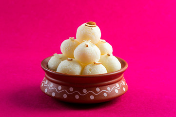 Indian Sweet or Dessert - Rasgulla, Famous Bengali sweet in clay bowl on a pink background.