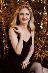 Christmas. Beautiful smiling woman. Makeup. Healthy long hair style. Elegant lady in dress over gold background. Happy new year. Fashion and vogue