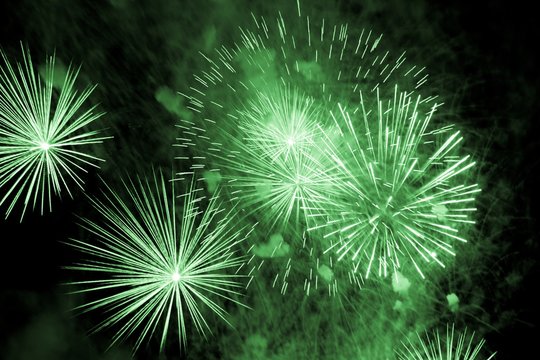 Luxury fireworks event sky show with green big bang stars. Premium entertainment magic star firework at e.g. New Years Eve or Independence Day party celebration. Black dark night background