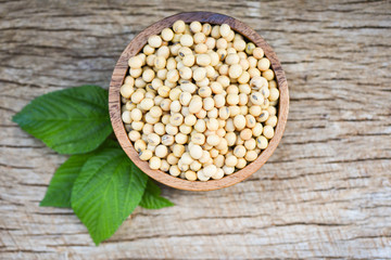 Soya , Soybean in a wooden bowl agricultural products on the wood background / dry soy beans and green leaf