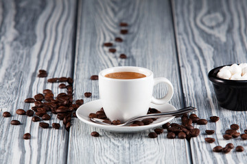 Cup of espresso on a wooden background with coffee beans on the table.