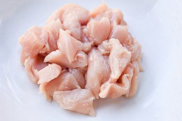 Pieces of raw chicken meat / fresh raw cut chicken fillet on white plate background