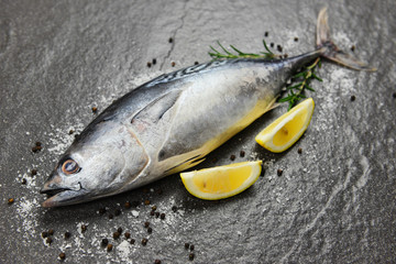 Fresh fish with herbs spices rosemary and lemon - Raw fish seafood on black plate background top view , Longtail tuna , Eastern little tuna fish