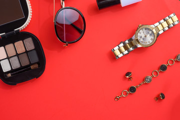 Flat lay.Women's accessories and blogging, red background with cosmetics, glasses and jewelry. Women's shops and retail sales