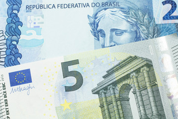 A five Euro bank note with a blue two Brazilian reais bill.  Shot in macro.