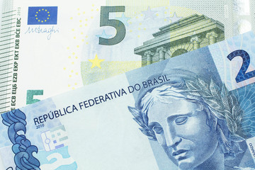 A five Euro bank note with a blue two Brazilian reais bill.  Shot in macro.
