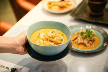 A woman's hand holding a shrimp curry dish