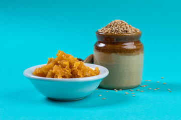 Sesame Seeds in clay pot with Jaggery in bowl on blue background