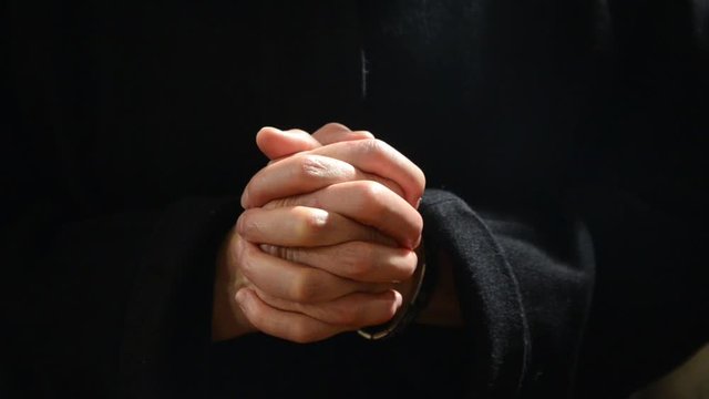 Praying Nun. Christmas Midnight Mass. Christian woman praying  in the church. Nun with hands crossed in Cathedral. Christianity and Religion