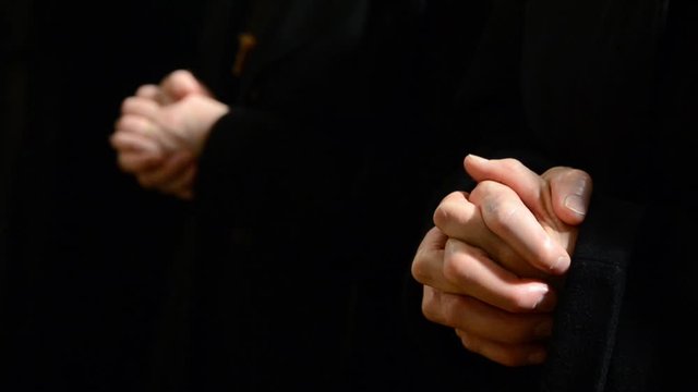 Praying Nuns. Christmas Midnight Mass. Christian women praying  in the church. Nuns with hands crossed in Cathedral. Christianity and Religion.
