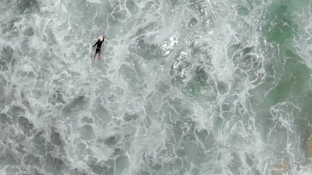 Aerial surfer paddling In The Waves Of Sea In Bali Indonesia