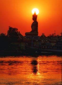 Big Buddha statue by the river at Wat Laem Suwannaram. Waterfront temple and fishing boat at Tha Chalom harbour at Mahachai with Tha Chalom Samut Sakhon Thailand. (Blur effect form camera)