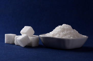 Sugar Cubes with Sugar in white plate on blue background