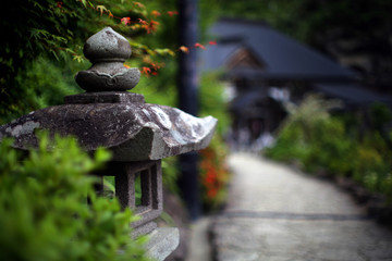 Beside the path leading to the ancient temple in Japan, a stone-made lamp holder revealing the calm atmosphere