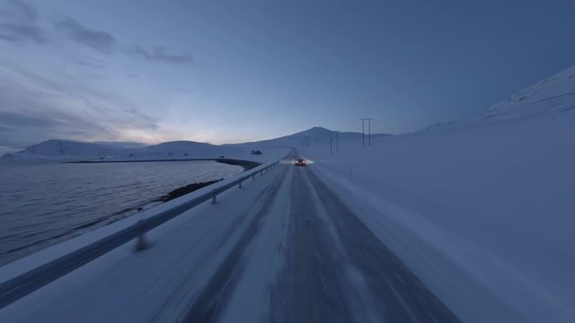 Aerial shot of fast supercar driving through a deserted winter landscape in Northern Norway.