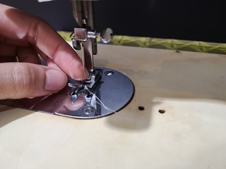 Seamstress installs the sewing machine to make the shirt. The close up picture shows the sewing equipment.